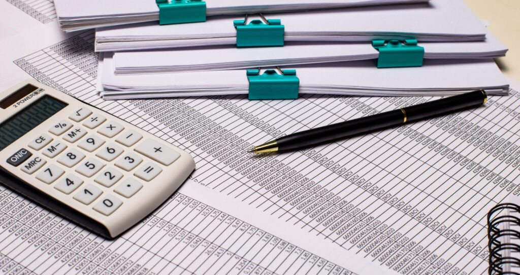 Calculator, financial paperwork and pen for company accounts